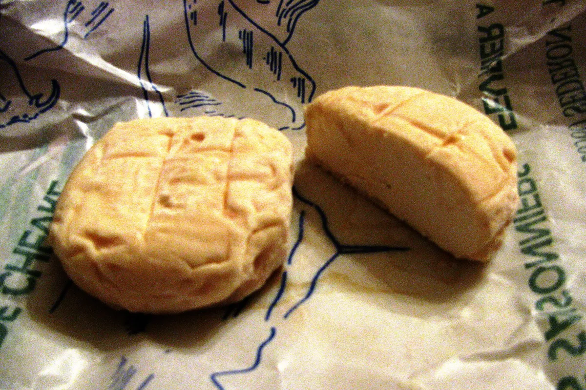 Deux petits fromages de chèvre ronds posés sur leur papier d'emballage, au marché de Séderon